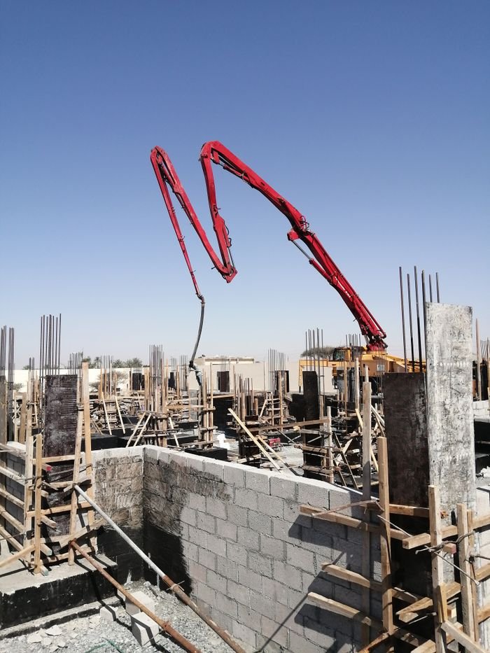 Concrete pump at a construction site under a clear sky in Al Dhaid, UAE. Urban development in progress.